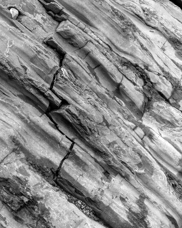 Layered rock strata fractured along the bedding planes, in black and white.